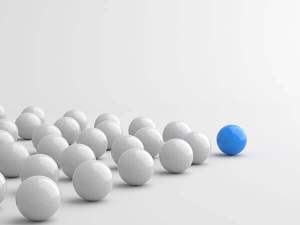 Several white balls being lead by a blue ball